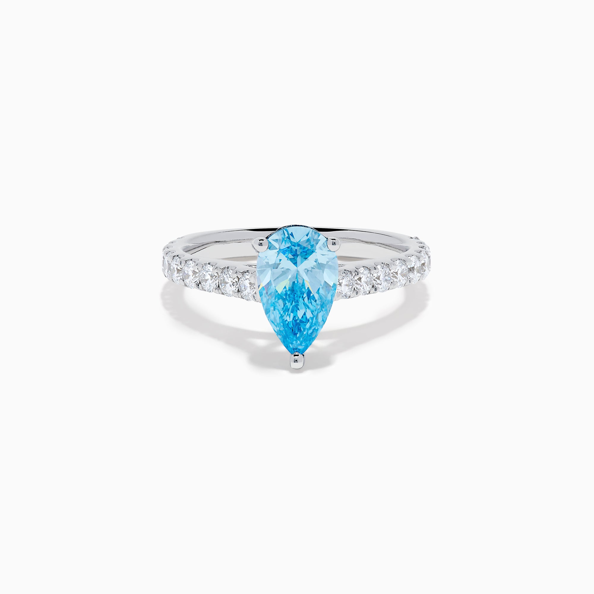 The Lab Grown Blue Diamond Solitaire Pear Ring in 14K White Gold features a striking pear-shaped blue diamond at the center, accented by a band adorned with small round white diamonds.