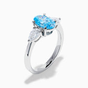 The Lab Grown Blue and White Diamond 3-Stone Ring in 14K White Gold showcases an oval blue centerpiece with two pear-shaped lab grown diamonds on each side, all set in elegant white gold.