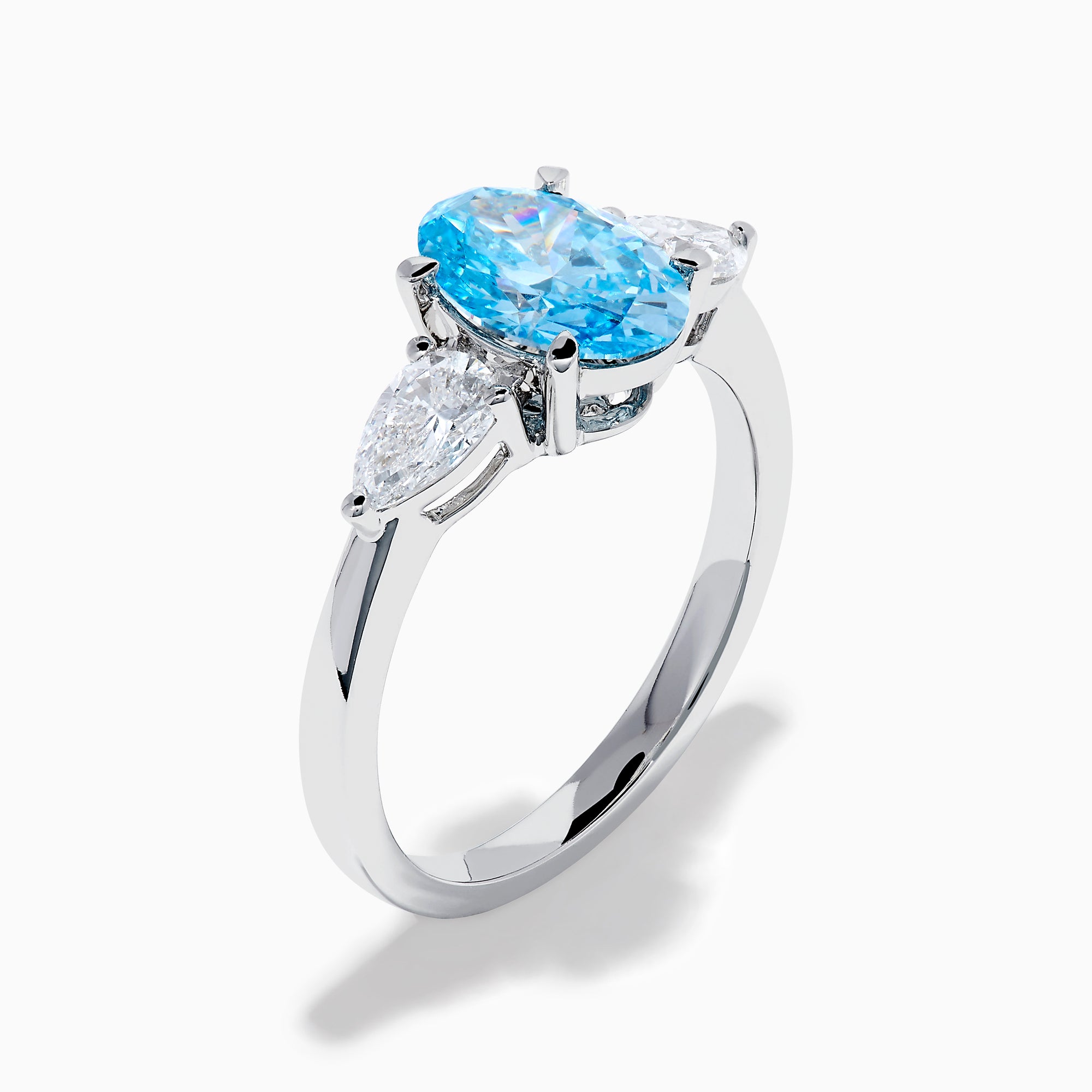 The Lab Grown Blue and White Diamond 3-Stone Ring in 14K White Gold showcases an oval blue centerpiece with two pear-shaped lab grown diamonds on each side, all set in elegant white gold.