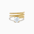 The Lab Grown Diamond Wrap around Round Ring in 14K Yellow Gold features a twisted triple-band design with a large round diamond center, shown against a white background.