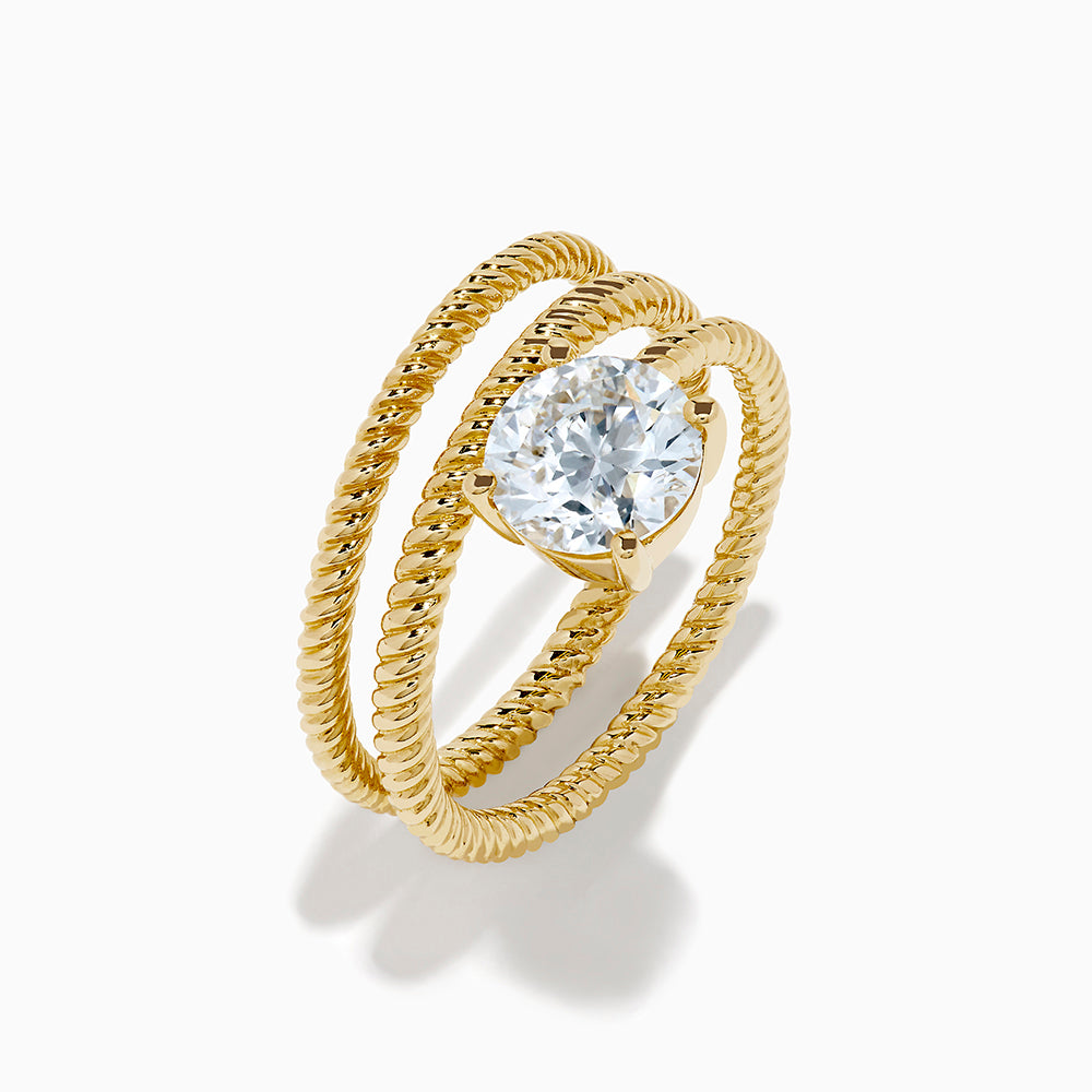 The Lab Grown Diamond Wrap around Round Ring in 14K Yellow Gold features a twisted triple-band design with a large round diamond center, shown against a white background.
