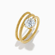 The Lab Grown Diamond Wrap around Round Ring in 14K Yellow Gold features a twisted triple-band design with a large round diamond center, shown against a white background.
