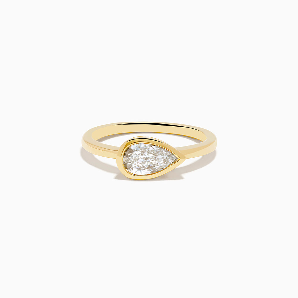 The Lab Grown Diamond East West Pear Ring in 14K Yellow Gold showcases a lab diamond in a pear shape, set horizontally in a sleek bezel on a plain band, presented against a white background.
