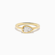 The Lab Grown Diamond East West Pear Ring in 14K Yellow Gold showcases a lab diamond in a pear shape, set horizontally in a sleek bezel on a plain band, presented against a white background.