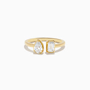 The Lab Grown Diamond Toi Et Moi Ring in 14K Yellow Gold features a pear-shaped diamond and an emerald-cut lab diamond set side by side on a plain gold band, displayed on a white background.