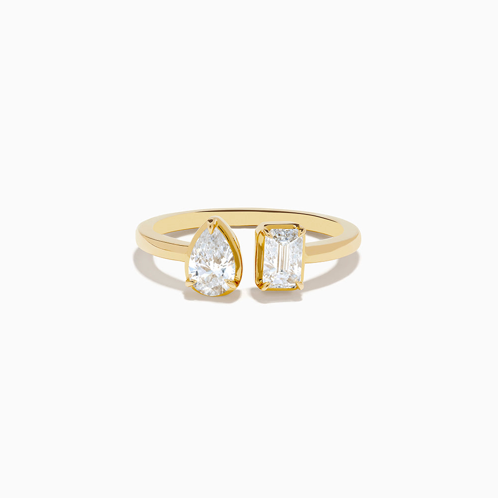 The Lab Grown Diamond Toi Et Moi Ring in 14K Yellow Gold features a pear-shaped diamond and an emerald-cut lab diamond set side by side on a plain gold band, displayed on a white background.