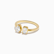The Lab Grown Diamond Toi Et Moi Ring in 14K Yellow Gold features a pear-shaped diamond and an emerald-cut lab diamond set side by side on a plain gold band, displayed on a white background.