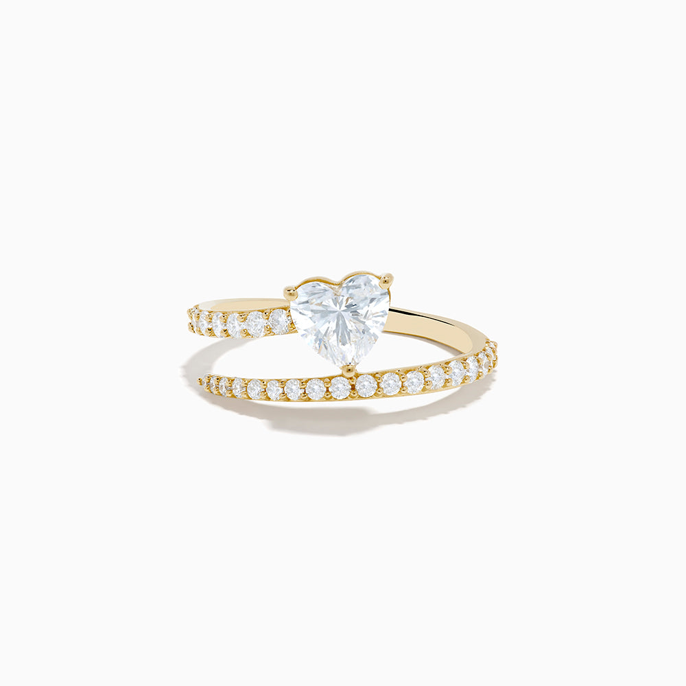 The Lab Grown Diamond Wrap Around Heart Ring in 14K Yellow Gold showcases a heart-shaped center stone and two open bands adorned with diamonds, elegantly displayed on a white background.