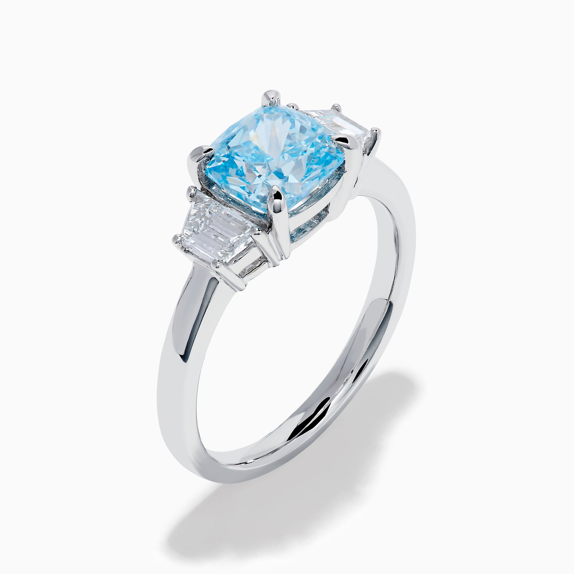 A Lab Grown Blue and White Diamond 3 Stone Ring in 14K White Gold showcases a central rectangular blue diamond flanked by two clear rectangular diamonds, set in gleaming white gold and displayed against a white background.