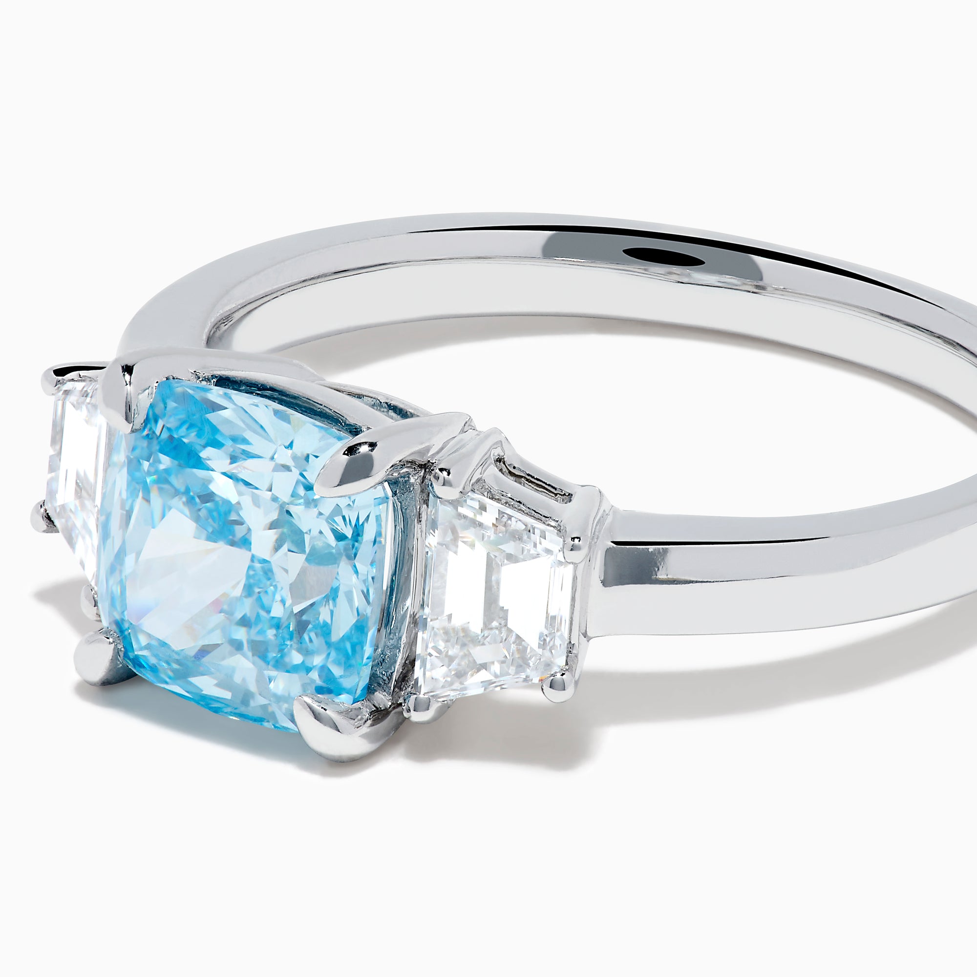 A Lab Grown Blue and White Diamond 3 Stone Ring in 14K White Gold showcases a central rectangular blue diamond flanked by two clear rectangular diamonds, set in gleaming white gold and displayed against a white background.