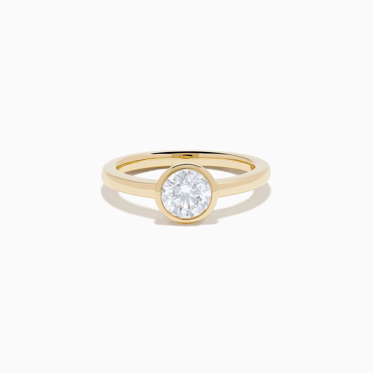 The Lab Grown Round Diamond Bezel Ring in 14K Yellow Gold features a simple band with a single bezel-set round white diamond at the center, shown on a white background.