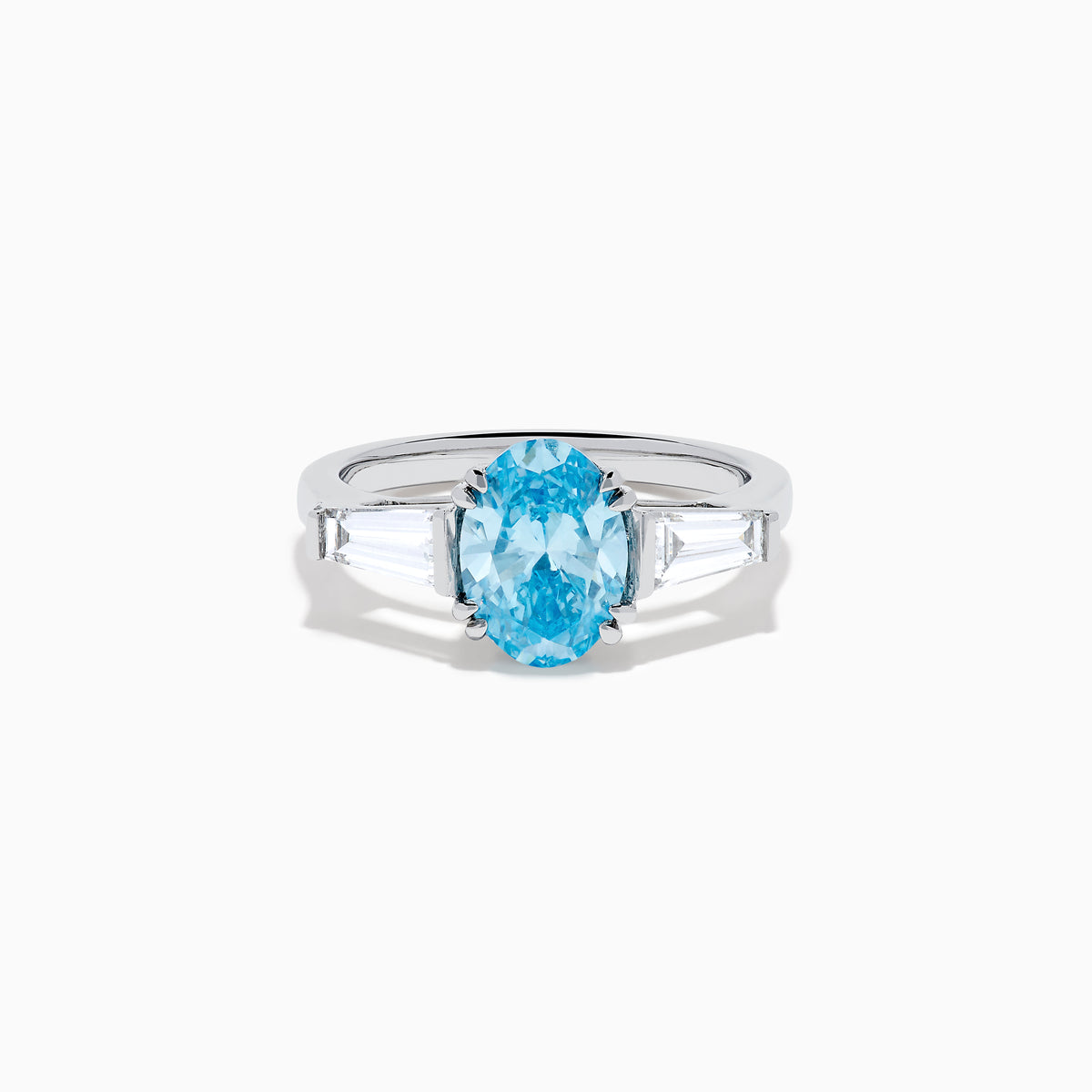 The Lab Grown Blue and White Diamond 3-Stone Ring in 14K White Gold showcases an oval blue diamond flanked by tapered white baguette diamonds, all set against a plain white background.