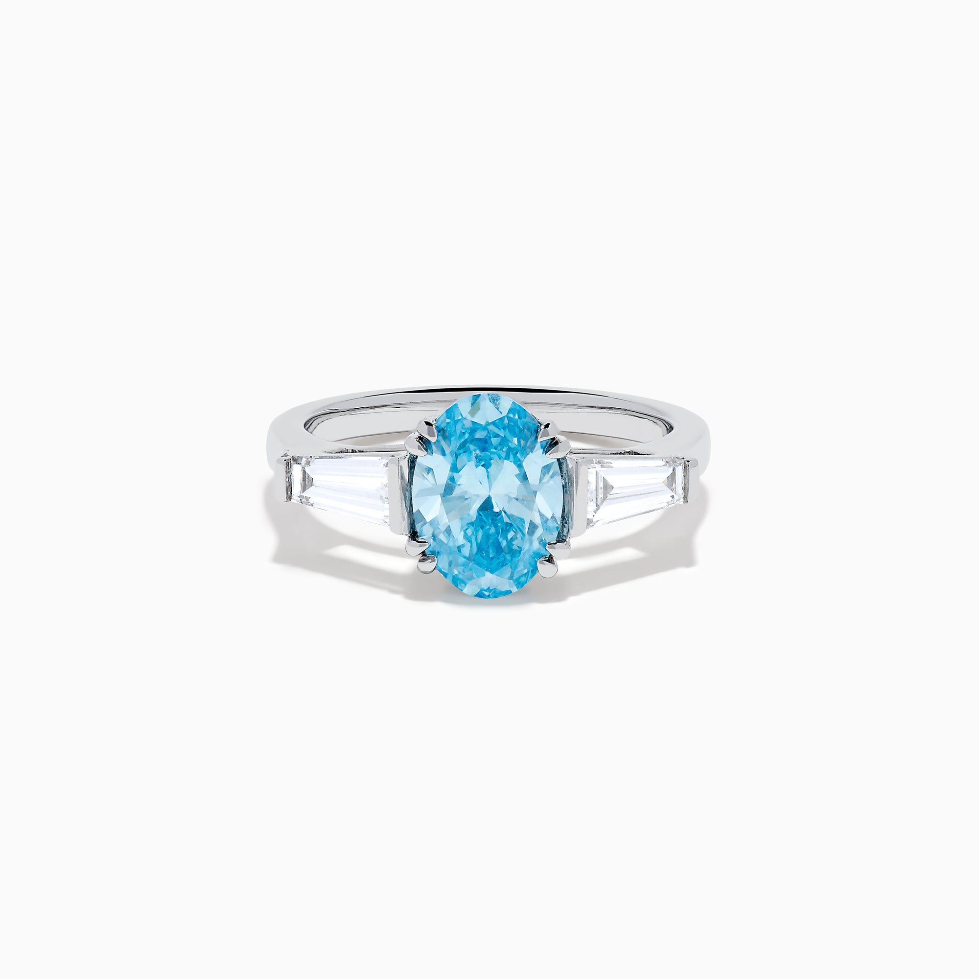 The Lab Grown Blue and White Diamond 3-Stone Ring in 14K White Gold showcases an oval blue diamond flanked by tapered white baguette diamonds, all set against a plain white background.