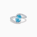 The Lab Grown Blue and White Diamond Connect Ring in 14K White Gold features an oval blue gemstone center, accented with lab grown diamonds on a curved band, shown against a plain white background.