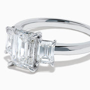 The Lab Grown Emerald Cut Diamond 3 Stone Ring in 14K White Gold features a central emerald-cut lab-grown diamond flanked by two rectangular diamonds on each side.