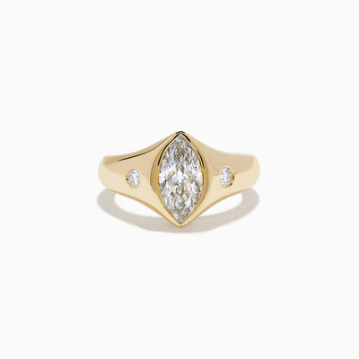 The Lab Grown Diamond Marquise Bezel Pinky Ring in 14K Yellow Gold features a central marquise lab grown diamond, accented by two small round diamonds on each side, all set on a sleek, polished band.