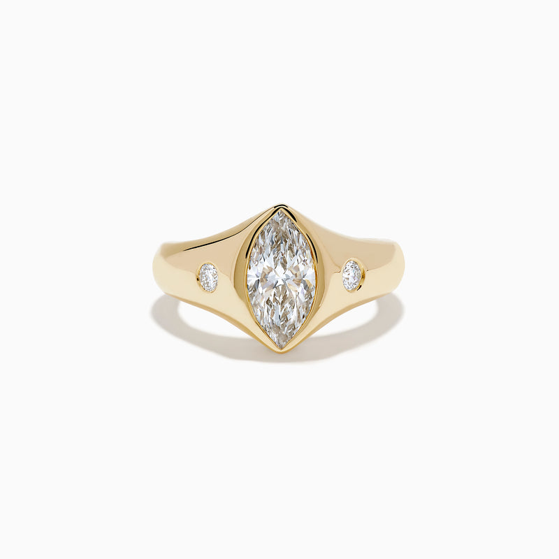 The Lab Grown Diamond Marquise Bezel Pinky Ring in 14K Yellow Gold features a central marquise lab grown diamond, accented by two small round diamonds on each side, all set on a sleek, polished band.