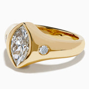 The Lab Grown Diamond Marquise Bezel Pinky Ring in 14K Yellow Gold features a central marquise lab grown diamond, accented by two small round diamonds on each side, all set on a sleek, polished band.