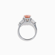 The Lab Grown Pink and White Diamond 3 Stone Ring in 14K White Gold features a striking round pink center stone with two rectangular white diamonds on each side, set against a white background.