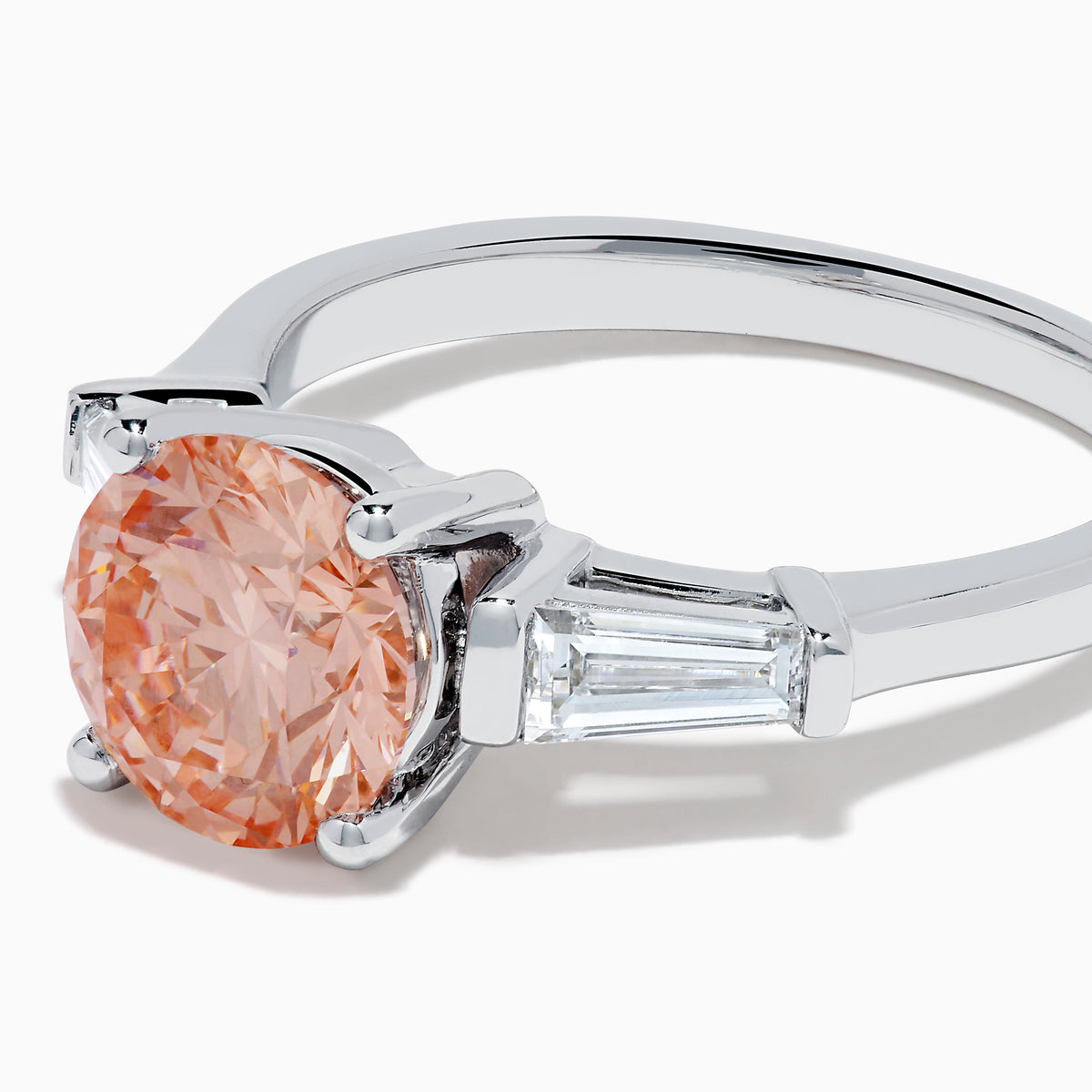 The Lab Grown Pink and White Diamond 3 Stone Ring in 14K White Gold features a striking round pink center stone with two rectangular white diamonds on each side, set against a white background.