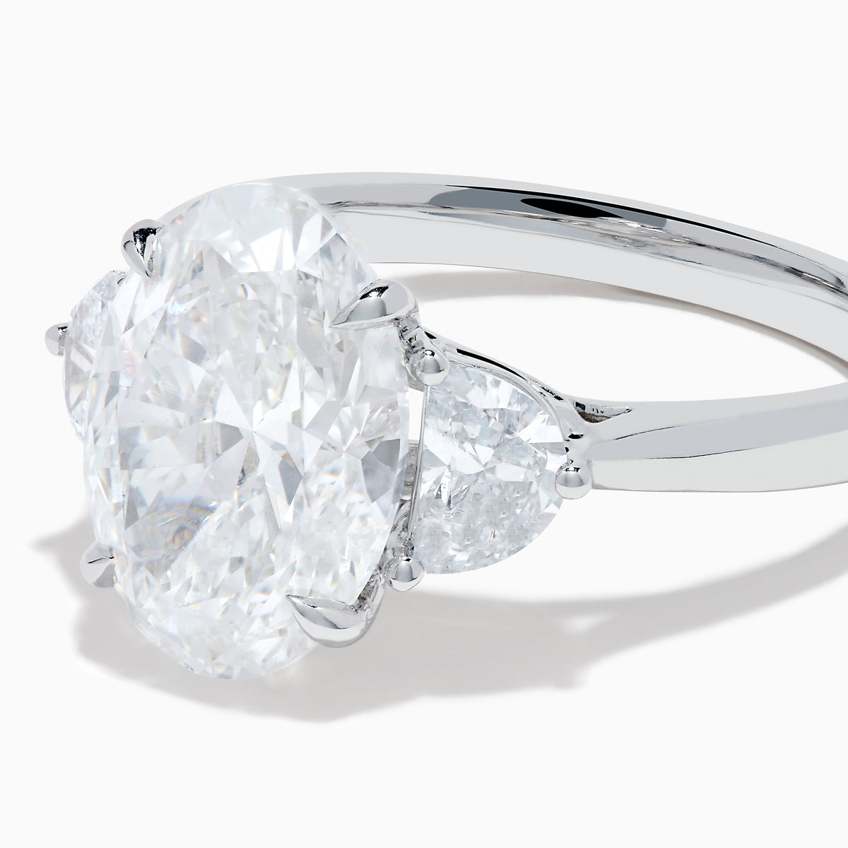 The Lab Grown Oval Diamond 3 Stone Ring in 14K White Gold features a striking lab grown oval diamond center, accented by two pear-shaped diamonds on each side.