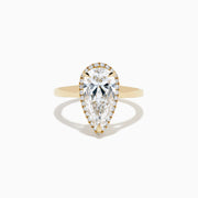 The Lab Grown Elongated Pear Shaped Diamond Halo Ring in 14K Yellow Gold features a large pear-shaped lab-grown diamond surrounded by a halo of smaller round diamonds, displayed on a plain white background.