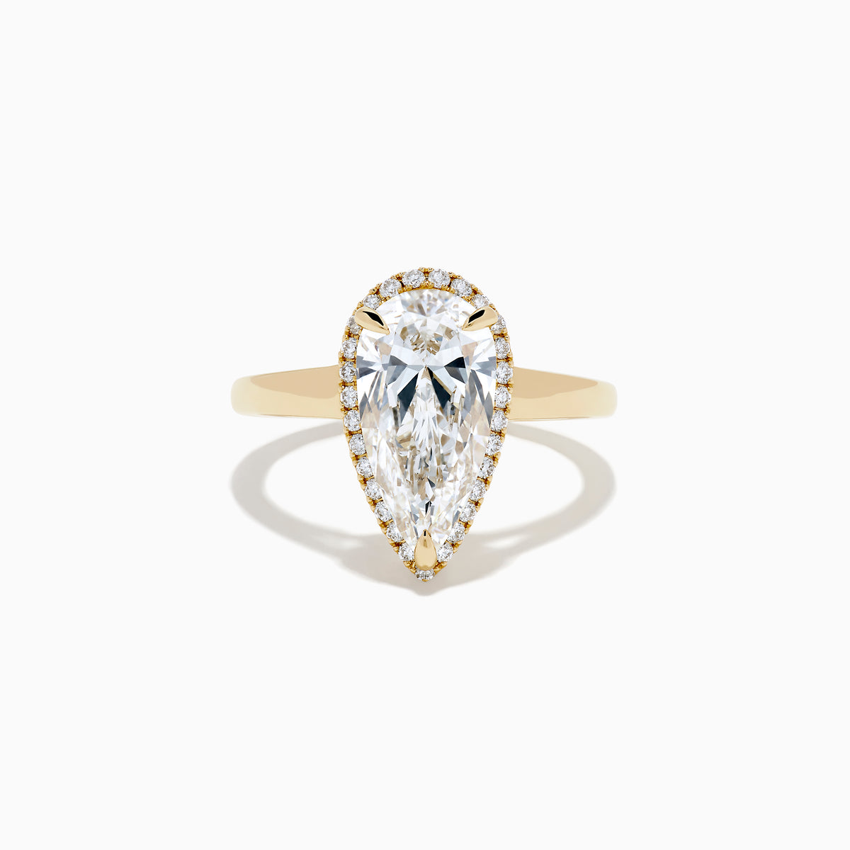 The Lab Grown Elongated Pear Shaped Diamond Halo Ring in 14K Yellow Gold features a large pear-shaped lab-grown diamond surrounded by a halo of smaller round diamonds, displayed on a plain white background.