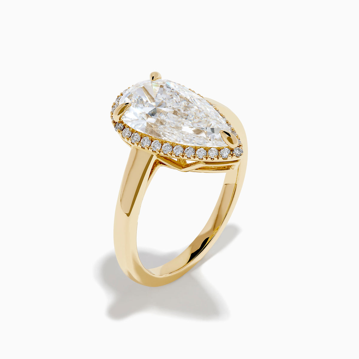 The Lab Grown Elongated Pear Shaped Diamond Halo Ring in 14K Yellow Gold features a large pear-shaped lab-grown diamond surrounded by a halo of smaller round diamonds, displayed on a plain white background.