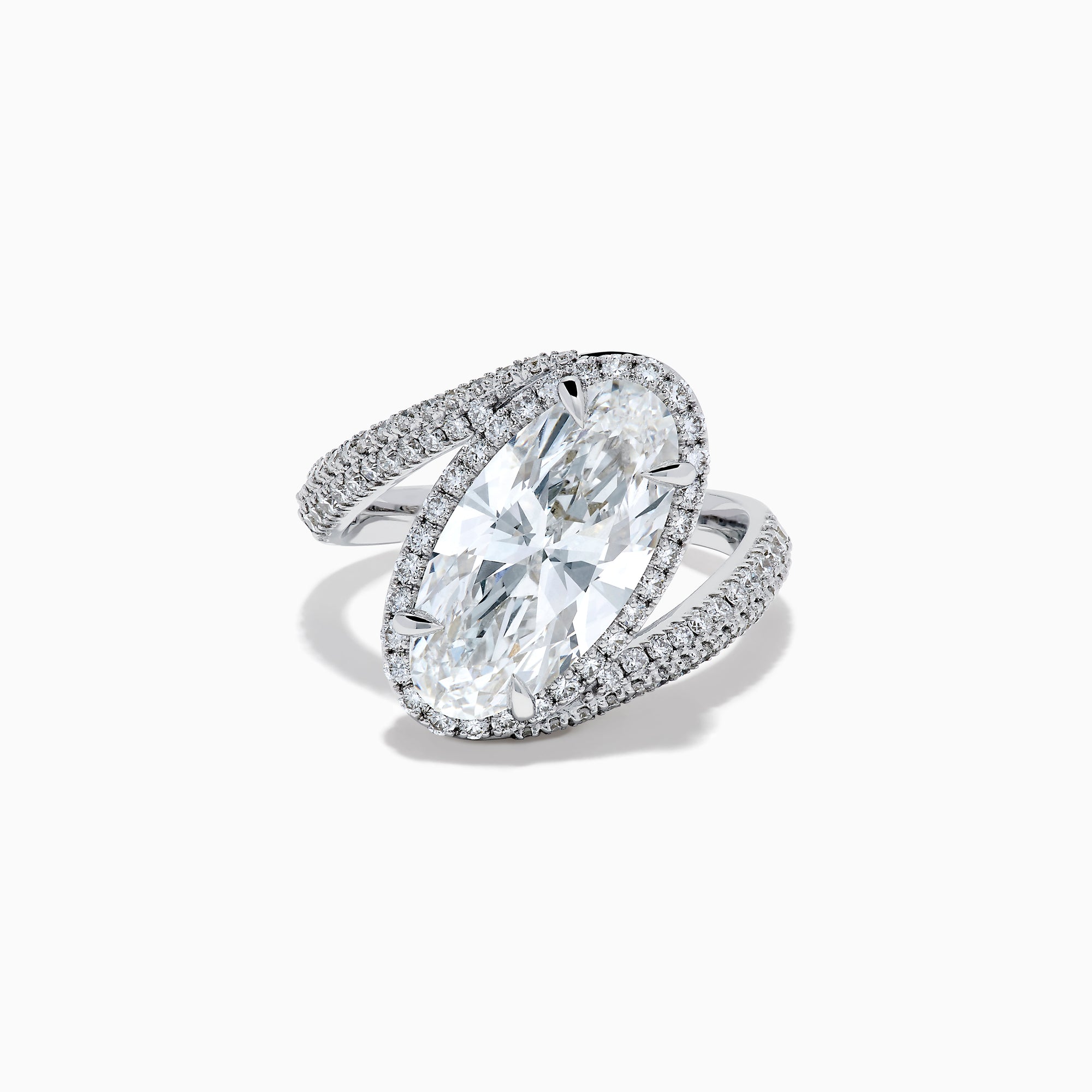 The Lab Grown Diamond Elongated Oval Halo Ring in 14K White Gold showcases a large oval lab diamond center, haloed by smaller diamonds with a diamond-adorned split shank, displayed on a clean white background.