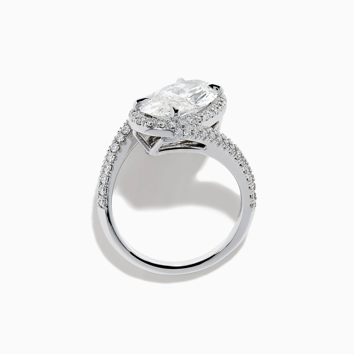The Lab Grown Diamond Elongated Oval Halo Ring in 14K White Gold showcases a large oval lab diamond center, haloed by smaller diamonds with a diamond-adorned split shank, displayed on a clean white background.