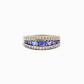 The Nahla Siri 14K Yellow Gold Tanzanite and Diamond Ring features a row of round blue tanzanite stones set between two rows of sparkling diamonds, shown on a white background.