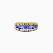 The Nahla Siri 14K Yellow Gold Tanzanite and Diamond Ring features a row of round blue tanzanite stones set between two rows of sparkling diamonds, shown on a white background.