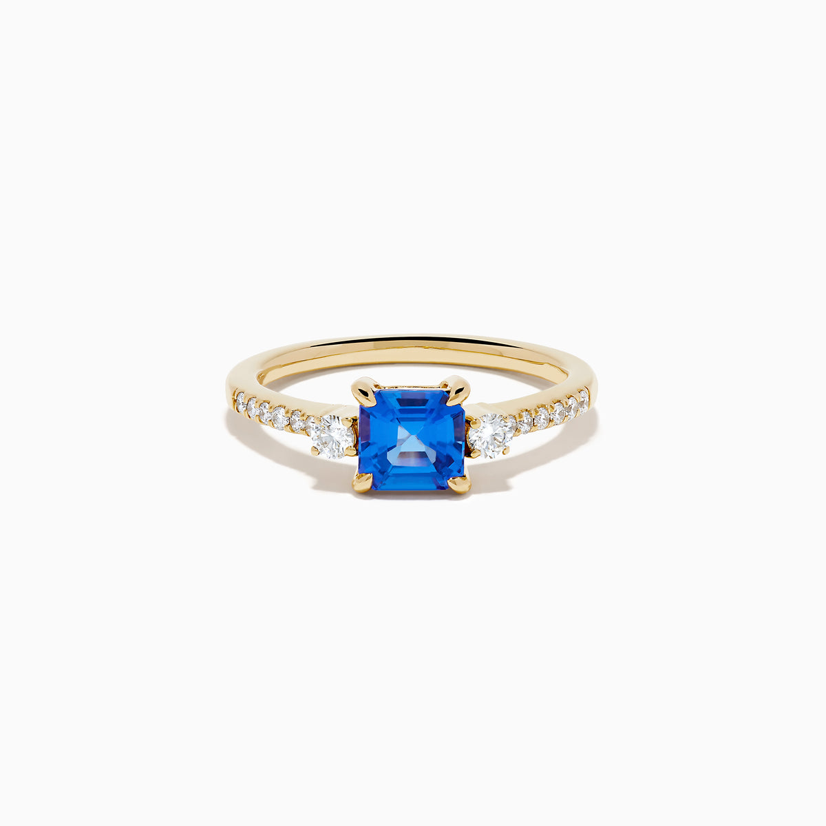 The 14K Yellow Gold Tanzanite and Diamond Ring showcases a square-cut blue tanzanite centerpiece, accented by round white diamonds set along the band.