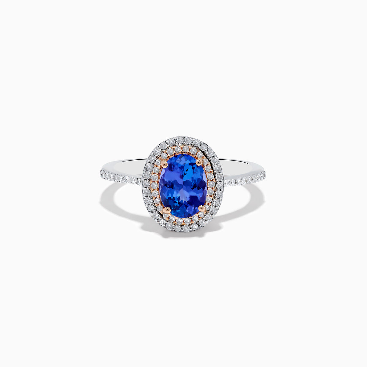 The Nahla Siri 14K Two Tone Tanzanite and Diamond Double Halo Ring features a large oval tanzanite center, double halo of white diamonds, and additional diamonds along the band.