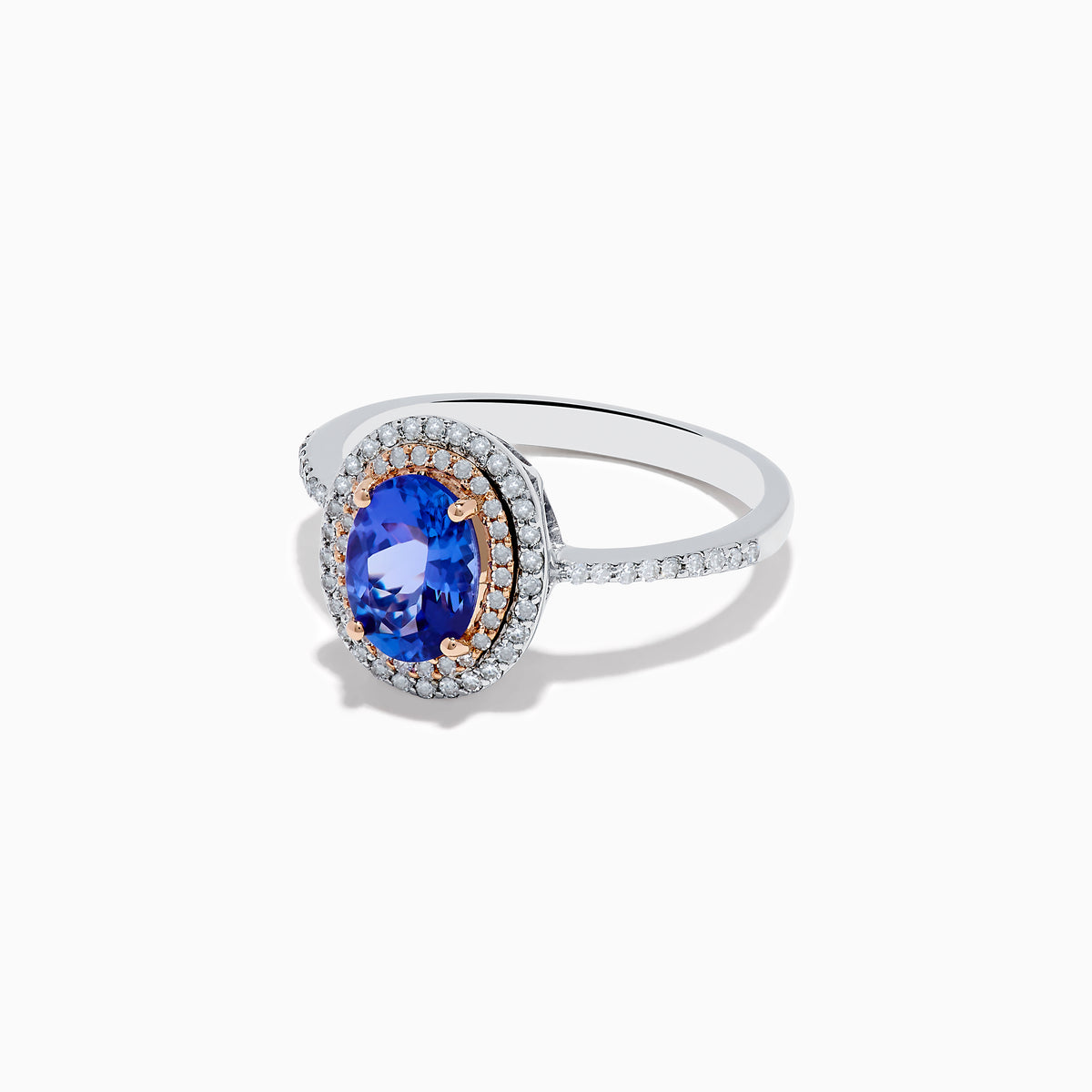 The Nahla Siri 14K Two Tone Tanzanite and Diamond Double Halo Ring features a large oval tanzanite center, double halo of white diamonds, and additional diamonds along the band.