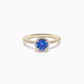 The Nahla 14K Yellow Gold Tanzanite and Diamond Ring showcases a round tanzanite center, encircled by a halo of clear diamonds and accented with additional diamonds along the band.