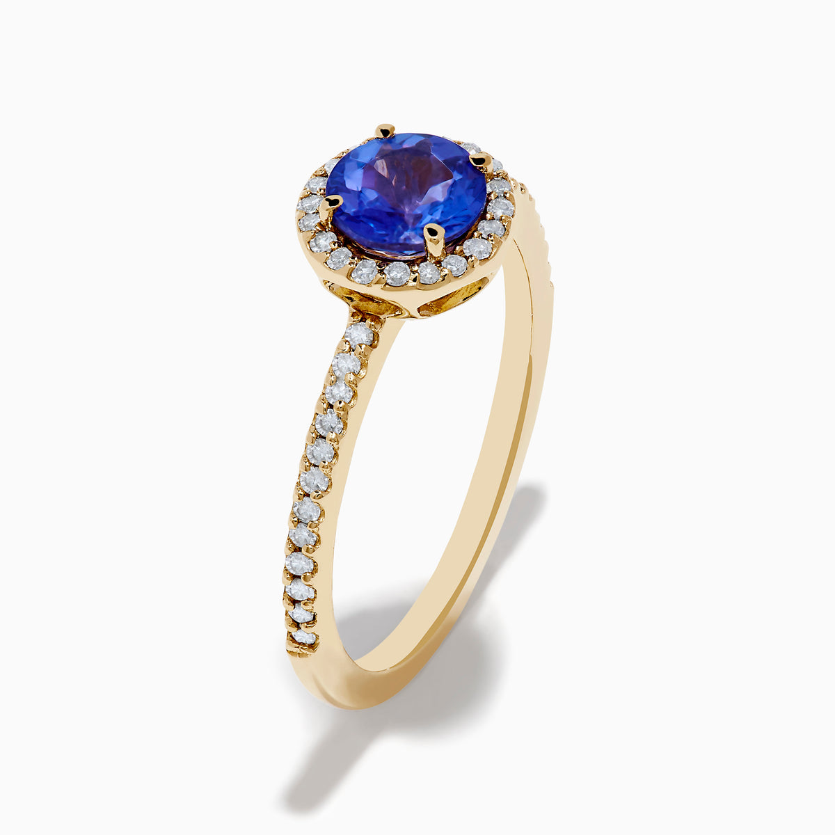 The Nahla 14K Yellow Gold Tanzanite and Diamond Ring showcases a round tanzanite center, encircled by a halo of clear diamonds and accented with additional diamonds along the band.