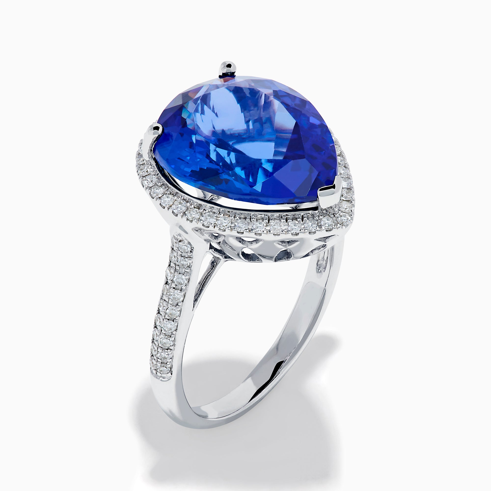 The 14K White Gold Pear Shape Tanzanite and Diamond Halo Ring features a pear-shaped blue tanzanite surrounded by a diamond halo on a delicate white gold band, displayed against a white background.