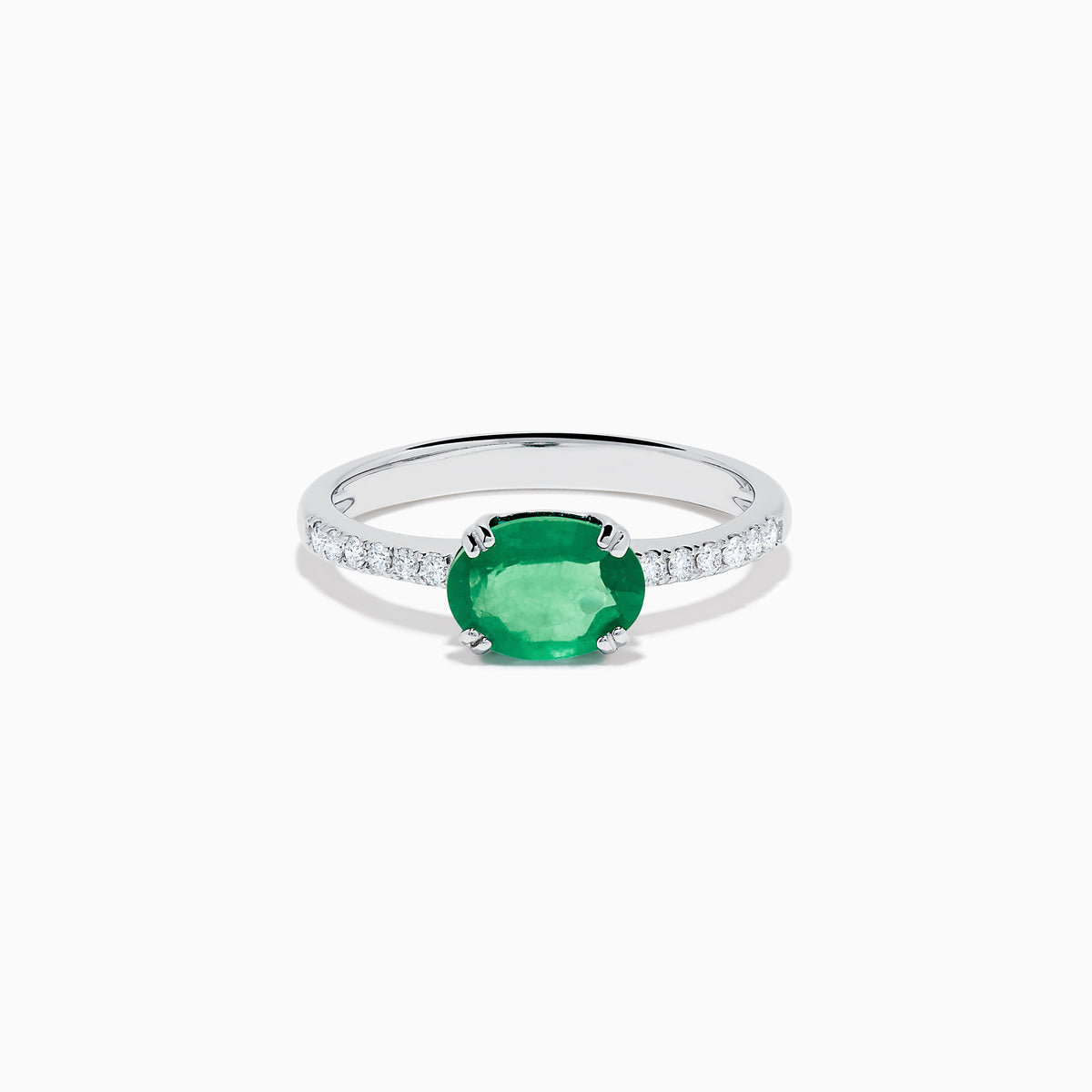 The 14K White Gold East West Oval Emerald and Diamond Ring showcases a striking green oval emerald set horizontally, accented by sparkling diamonds along the band.