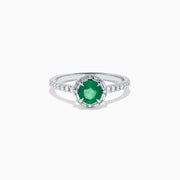 Introducing the 14K White Gold Emerald and Diamond Baguette Halo Ring, showcasing a round green emerald center stone, diamond baguette halo, and a band embellished with shimmering clear stones for added elegance.