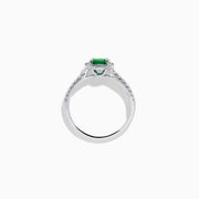 Introducing the 14K White Gold Emerald and Diamond Baguette Halo Ring, showcasing a round green emerald center stone, diamond baguette halo, and a band embellished with shimmering clear stones for added elegance.