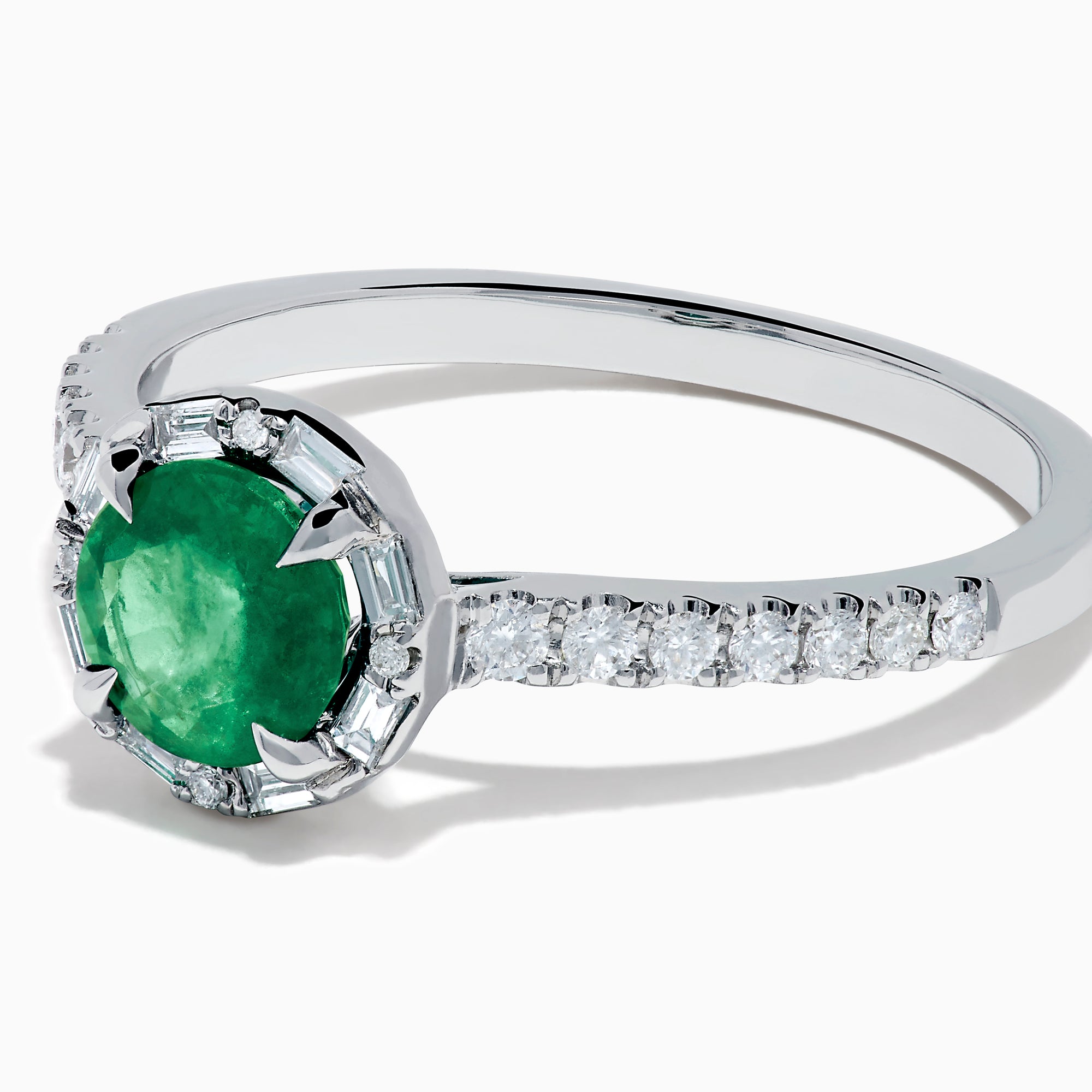 Introducing the 14K White Gold Emerald and Diamond Baguette Halo Ring, showcasing a round green emerald center stone, diamond baguette halo, and a band embellished with shimmering clear stones for added elegance.