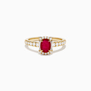 The 14K Yellow Gold Oval Ruby and Diamond Halo Ring features a central oval ruby surrounded by a sparkling diamond halo, with additional diamonds adorning the elegant band.