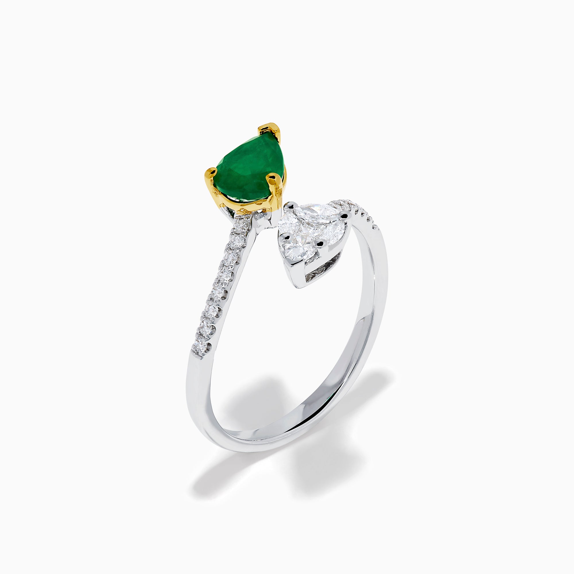 The 14K Two Tone Gold Emerald and Diamond Toi et Moi Ring features a pear-shaped green emerald and a pear-shaped white diamond, accented by sparkling small diamonds on the band.