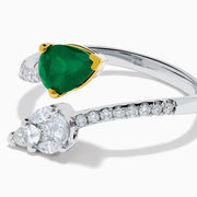 The 14K Two Tone Gold Emerald and Diamond Toi et Moi Ring features a pear-shaped green emerald and a pear-shaped white diamond, accented by sparkling small diamonds on the band.