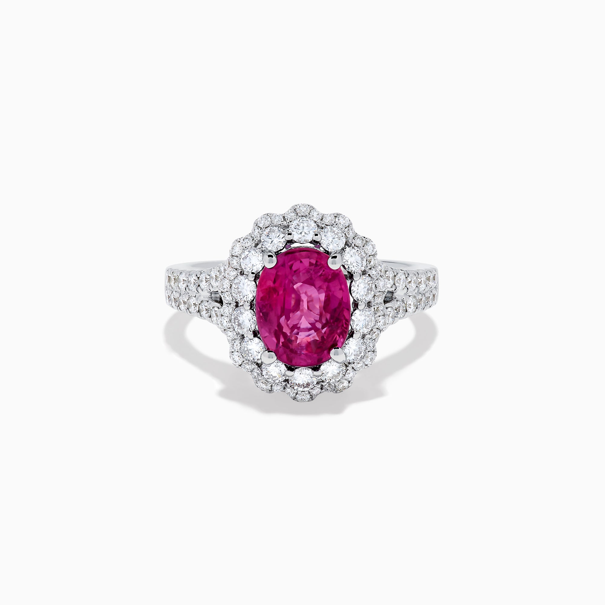 The 18K White Gold Pink Sapphire and Diamond Halo Ring features an oval pink sapphire surrounded by a diamond halo, with additional diamonds along the band for extra sparkle.