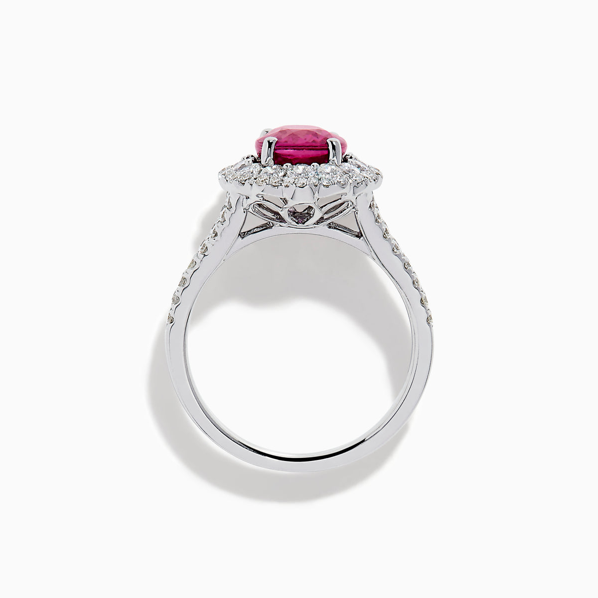 The 18K White Gold Pink Sapphire and Diamond Halo Ring features an oval pink sapphire surrounded by a diamond halo, with additional diamonds along the band for extra sparkle.