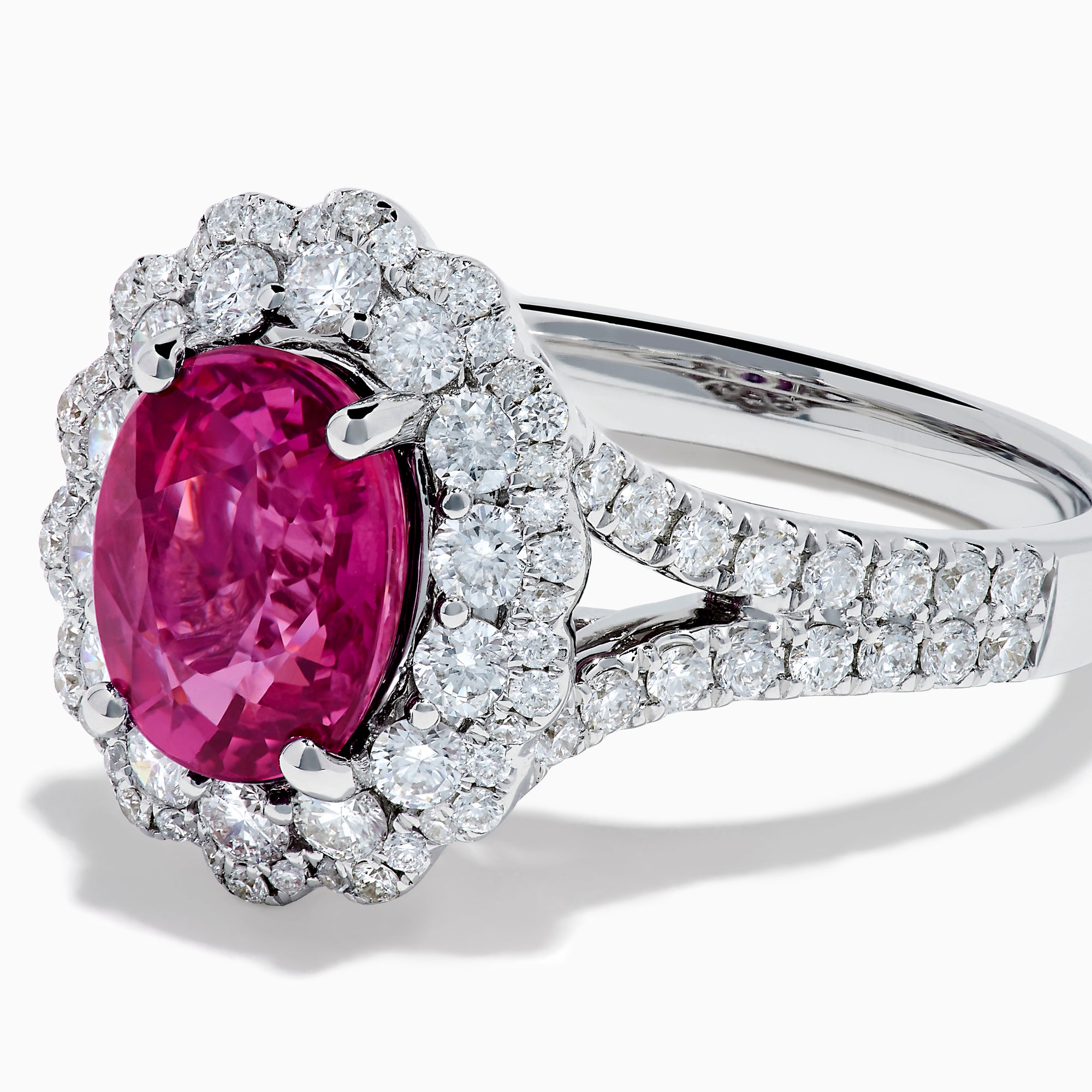 The 18K White Gold Pink Sapphire and Diamond Halo Ring features an oval pink sapphire surrounded by a diamond halo, with additional diamonds along the band for extra sparkle.
