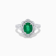 The 18K White Gold Emerald and Diamond Ring features an oval green emerald center stone, two diamond halos, and sparkling diamonds set along the band.