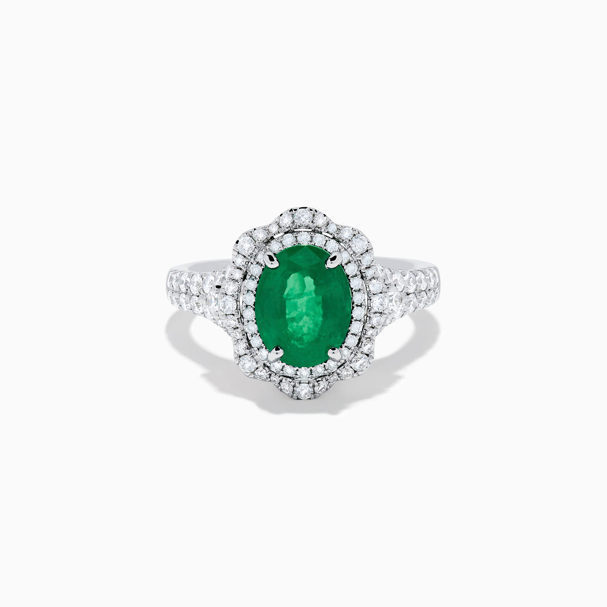 The 18K White Gold Emerald and Diamond Ring features an oval green emerald center stone, two diamond halos, and sparkling diamonds set along the band.